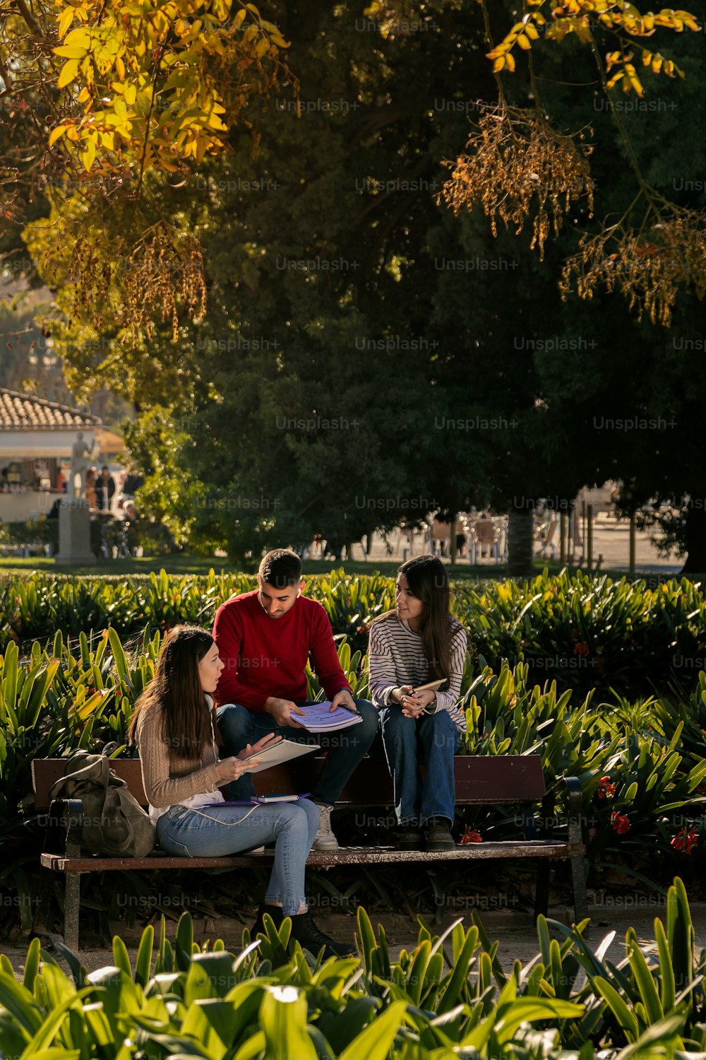 Small group of college friends studying on campus. College life, passing and preparing. Two girls and one boy.