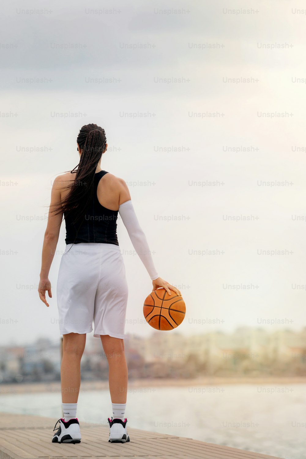 Giocatore di basket che tiene la palla con una mano, stile di vita. Foto da dietro