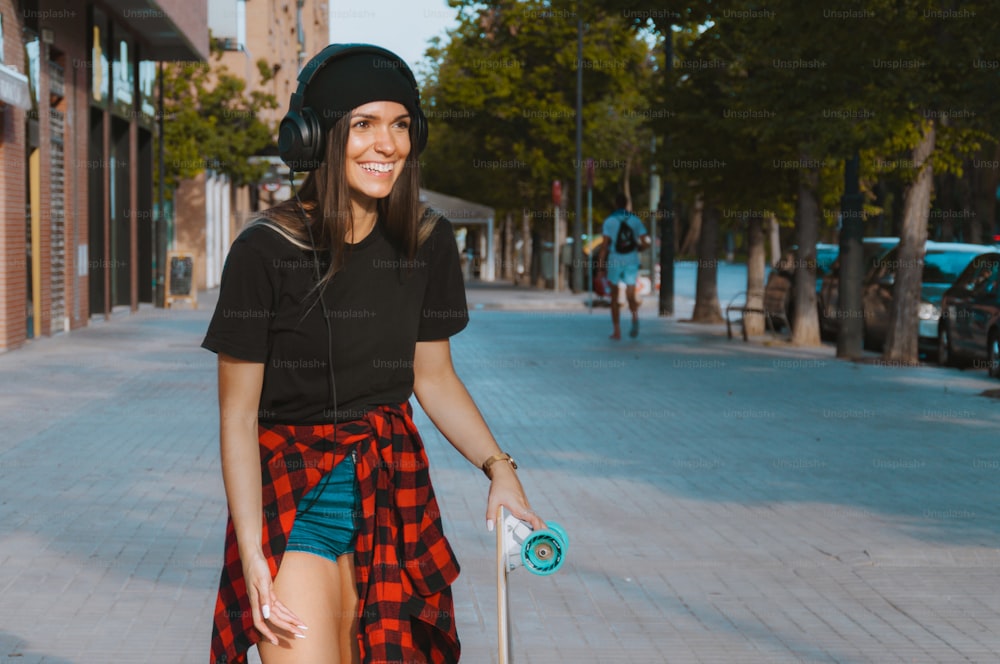 通りにスケートボードで立つ笑うラテンの女の子。屋外。スペースをコピーします。若者のサブカルチャーの概念。