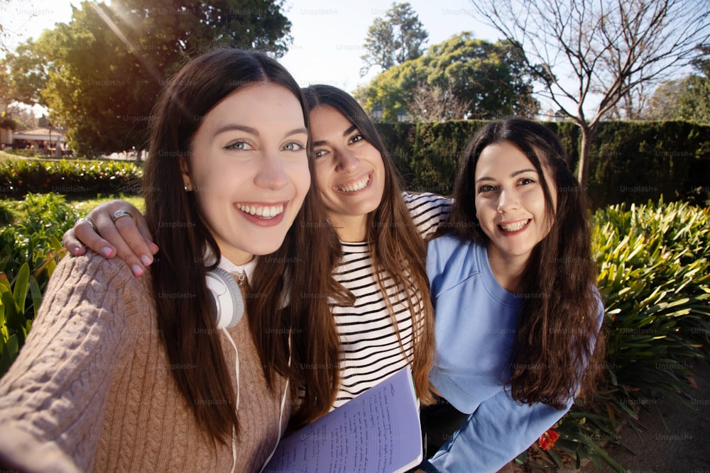 Three happy female students taking a picture of each other. Real life friends moment. Three students having fun together on college campus taking a photo.