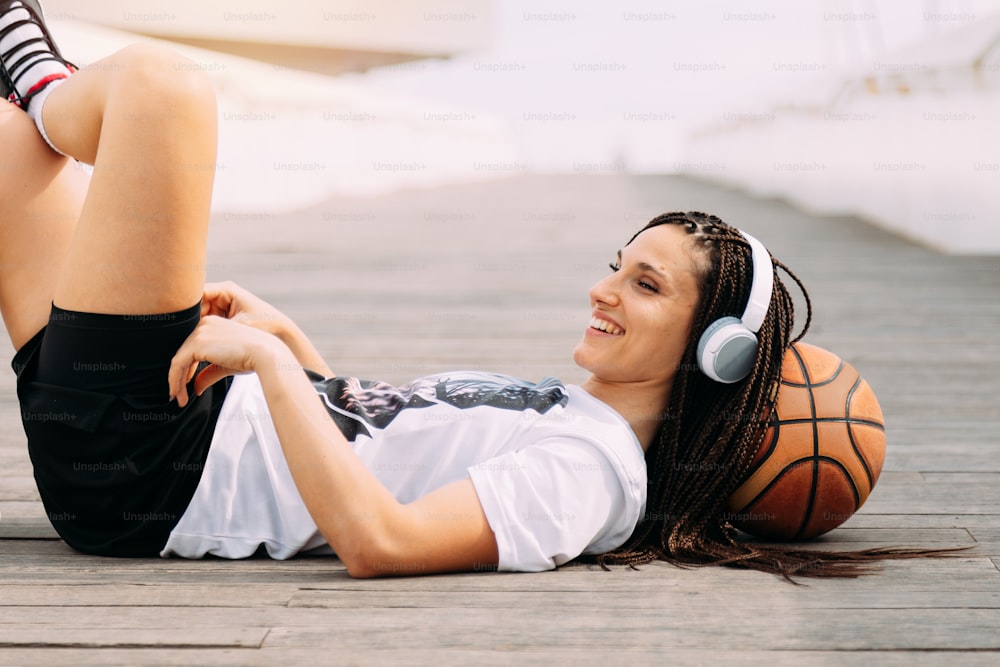 Femme souriante, heureuse et détendue allongée avec le basket. Sports et temps libre