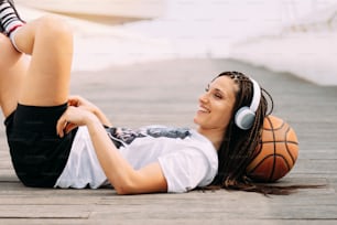 Smiling, happy and relaxed woman lying down with basketball. Sports and free time