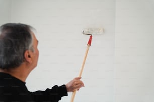 한 남자가 페인트 롤러로 벽을 칠하고 있다