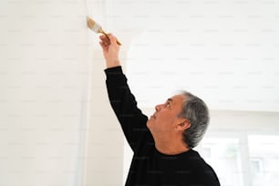 a man painting a wall with a brush