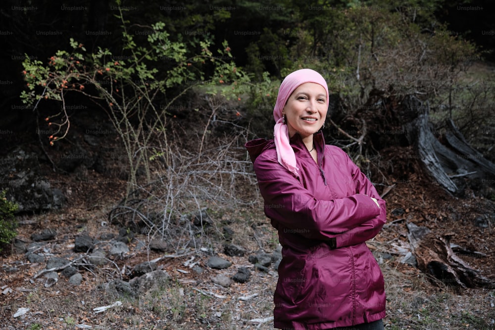 woman with pink headscarf, has cancer and is in the middle of the forest resting