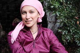 Porträt einer jungen Frau, die mit einem rosa Schal gegen Krebs kämpft und in die Kamera schaut. Echte Menschen im Gesundheitskonzept.