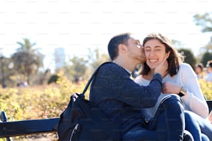Beautiful young couple who kiss on the cheek in an outdoor park