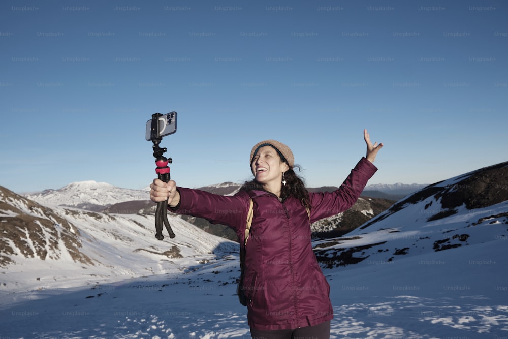 feliz mujer hispana adulta tomando un autorretrato en las nevadas montañas del sur