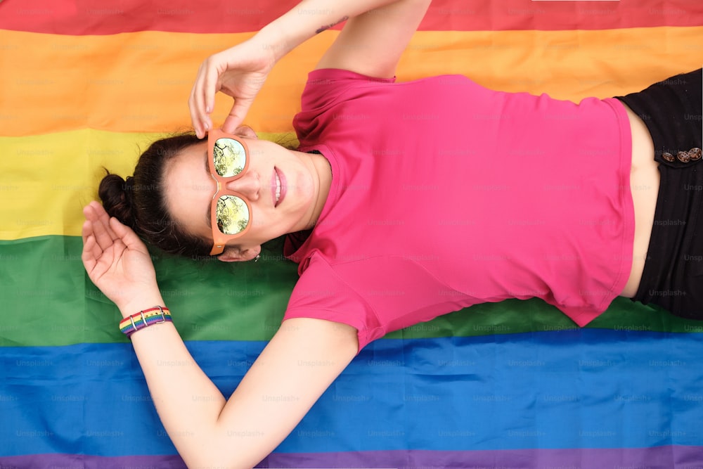 Vue de dessus d’une militante pour les droits à la diversité de genre allongée sur un drapeau de la fierté LGBTI.