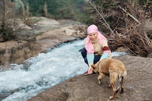 young woman with cancer playing with a dog on a river bank