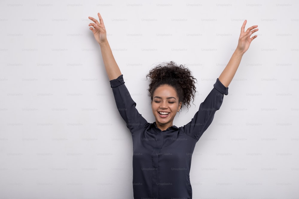 Femme heureuse levant les mains en l’air, vêtue d’une chemise