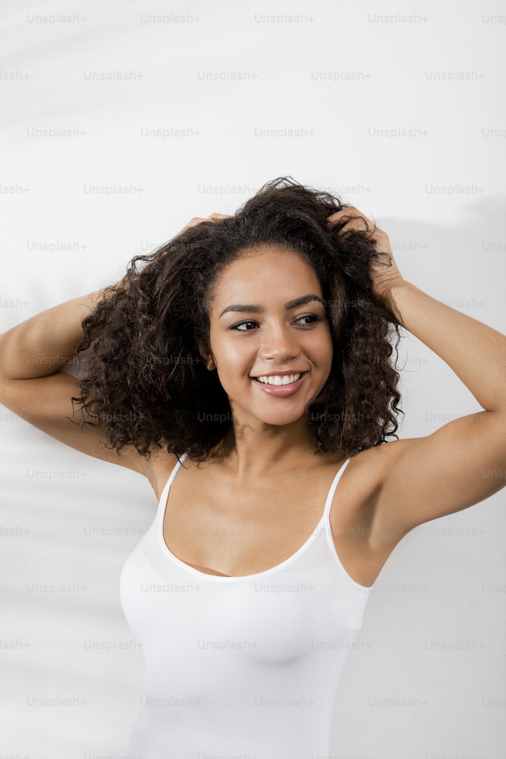 Brunette woman with hands in hair smiling and looking away