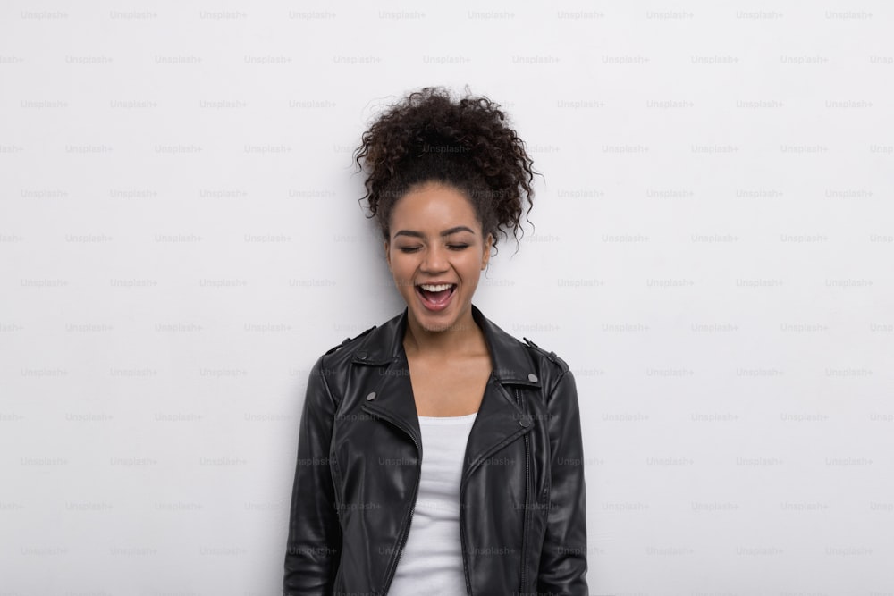Laughing brunette woman with her eyes closed over a white wall