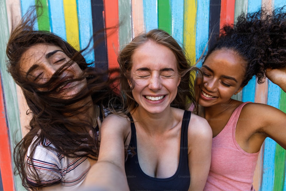 Giovani donne che scattano selfie all'aperto mentre il vento soffia i capelli