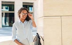 Young businesswoman holding her eyeglasses. Entrepreneur standing outdoors.