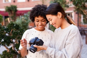 Smiling blogger and her photographer looking at digital camera after shooting