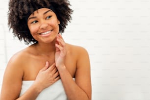 Smiling woman in front of a mirror. Young female admiring her face with natural scrub.