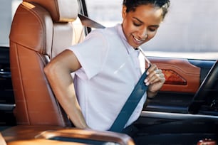 Young businesswoman fastening her seat belt in a car