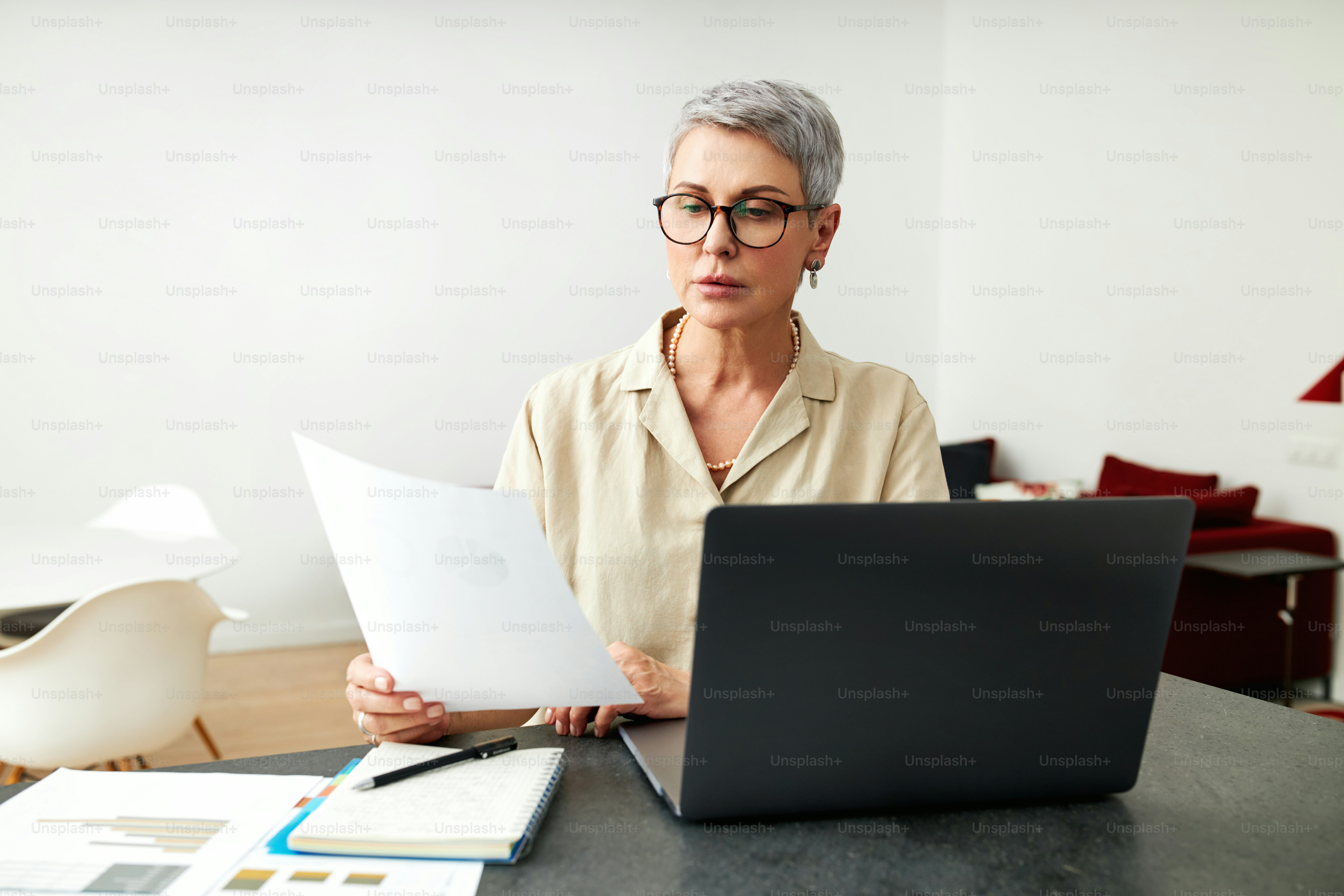 Donna matura con i documenti che usano il computer portatile