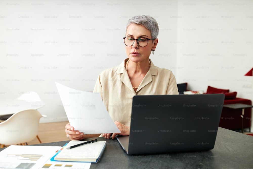Mature woman with documents using laptop