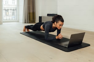 Young fit woman doing plank on mat at home