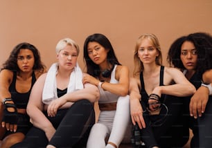 フィットネスアクセサリー付きのスポーツウェアを着た5人の自信のある女性。カメラを見ているさまざまな民族の若いスポーツ女性のグループ。
