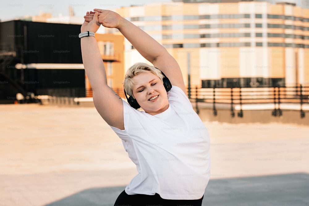 Happy woman with plus size body doing warming up exercises before workout on a roof