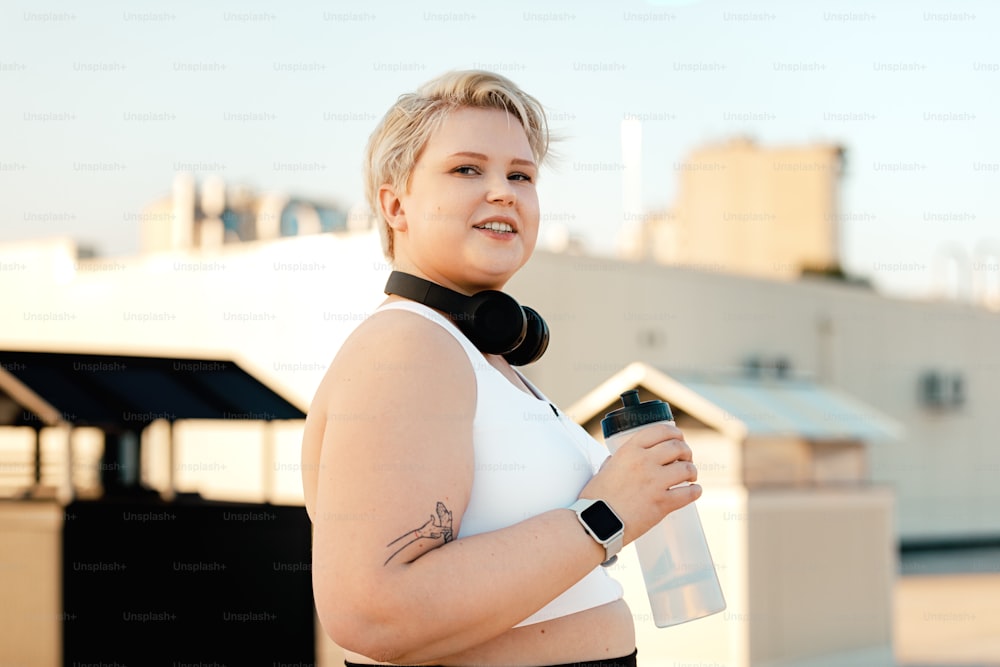 Portrait of a young curvy woman holding a bottle taking a break during training