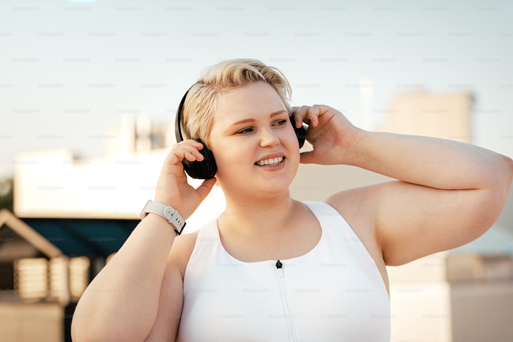 Mujer de talla grande escuchando música en el techo durante el entrenamiento