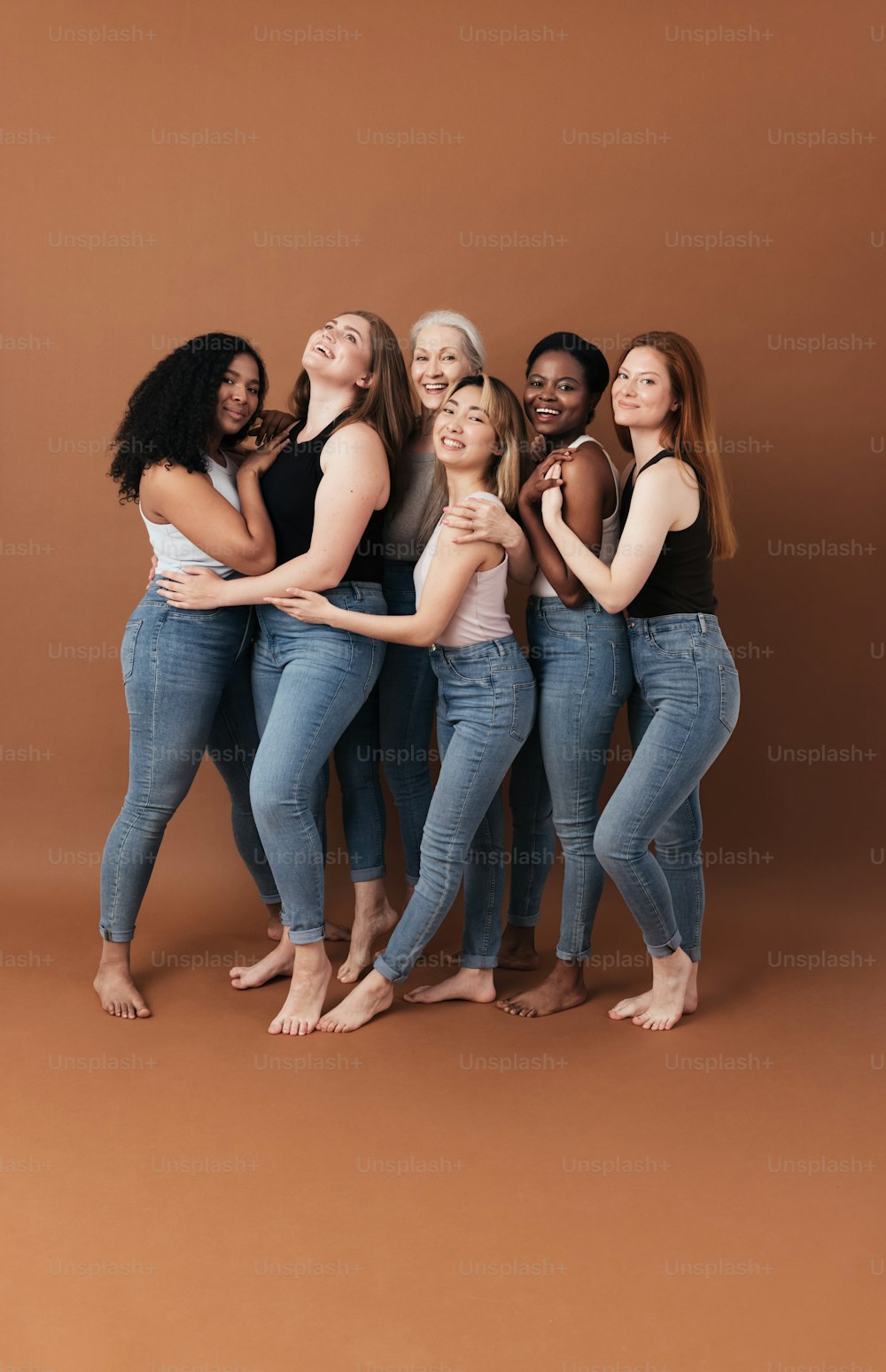 Group of cheerful women of different body type and ages standing together in a studio