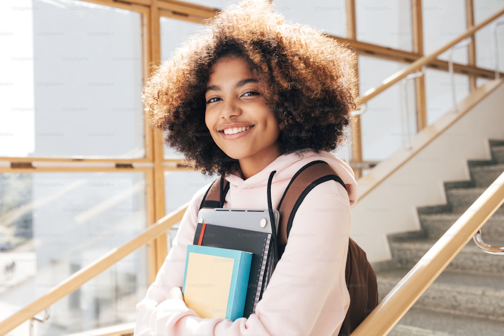 Portrait of beautiful girl with curly hair standing on stairs in school