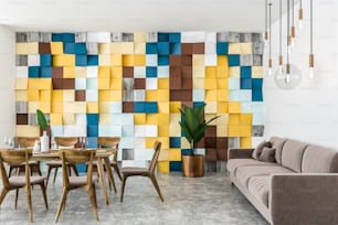 Elegante sala da pranzo interna con parete piastrellata colorata, pavimento in cemento, lungo tavolo in legno con sedie e lungo divano beige. Rendering 3D