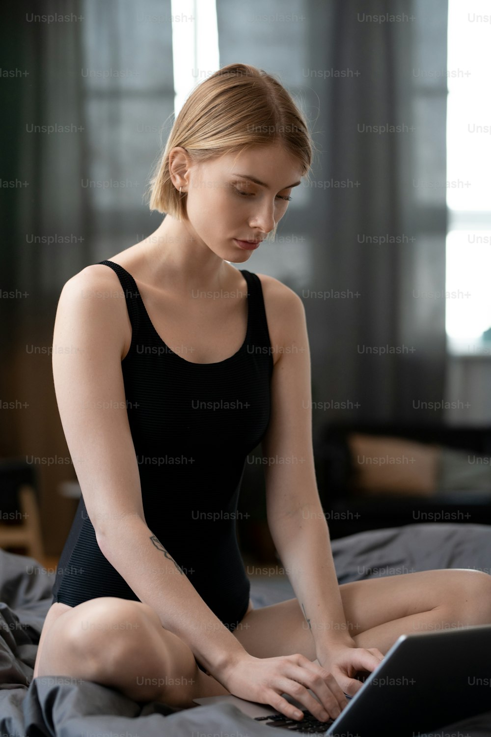 Young woman sitting on the bed and typing on laptop she working online at home