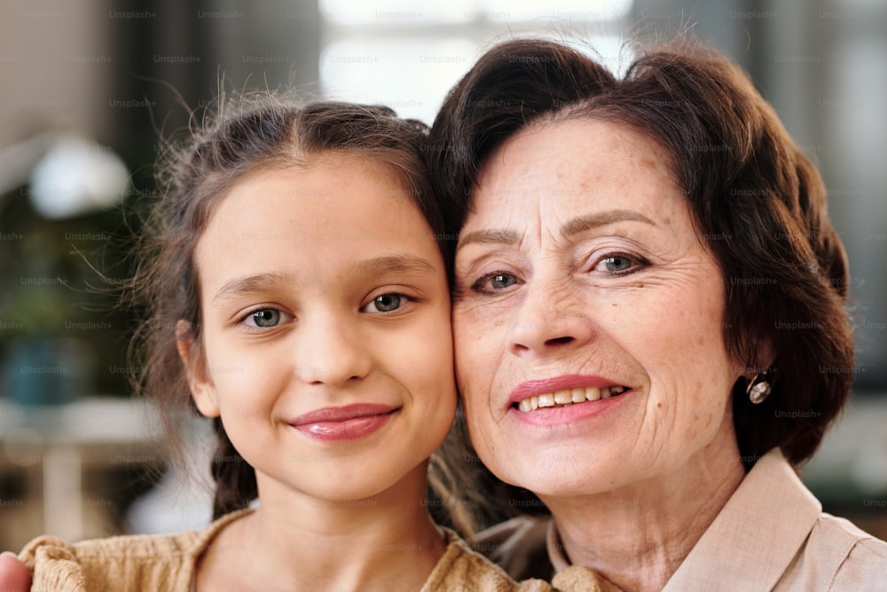 Faces of affectionate mature female and cute little girl