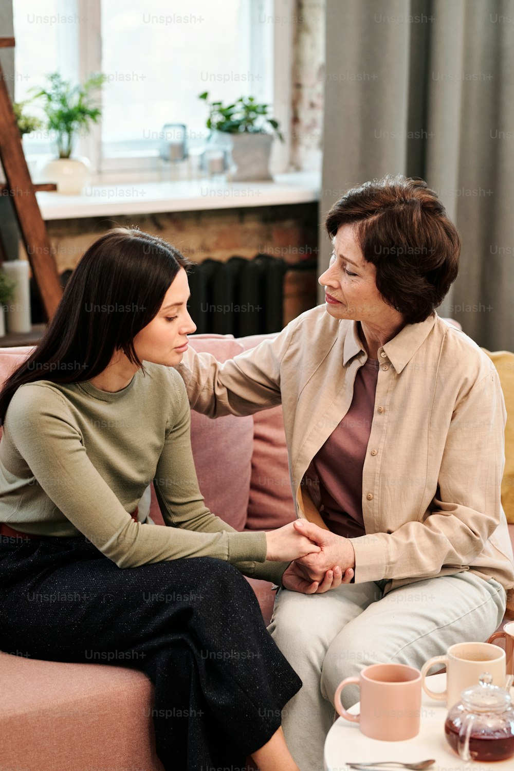 Mature woman comforting her upset daughter in home environment