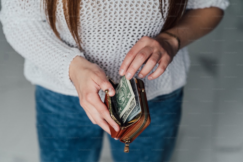 Una mujer sostiene una billetera y dinero