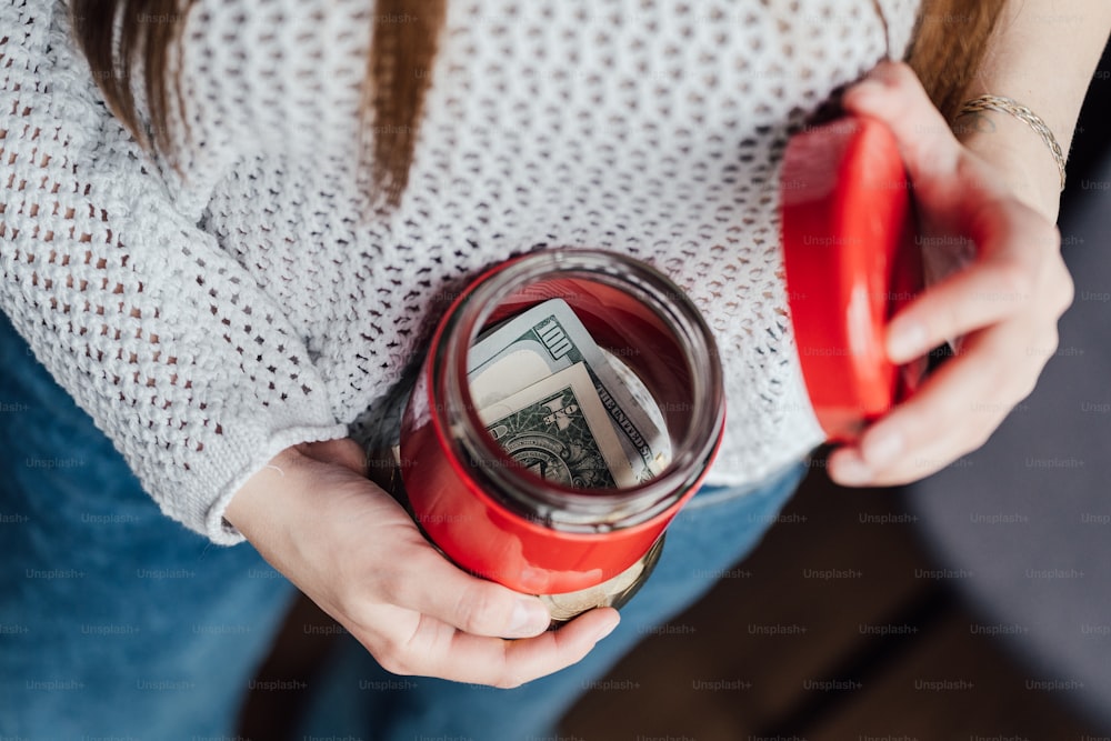 uma mulher segurando um copo vermelho com dinheiro nele