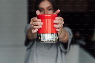 Une femme tenant une tasse rouge avec de l’argent dedans