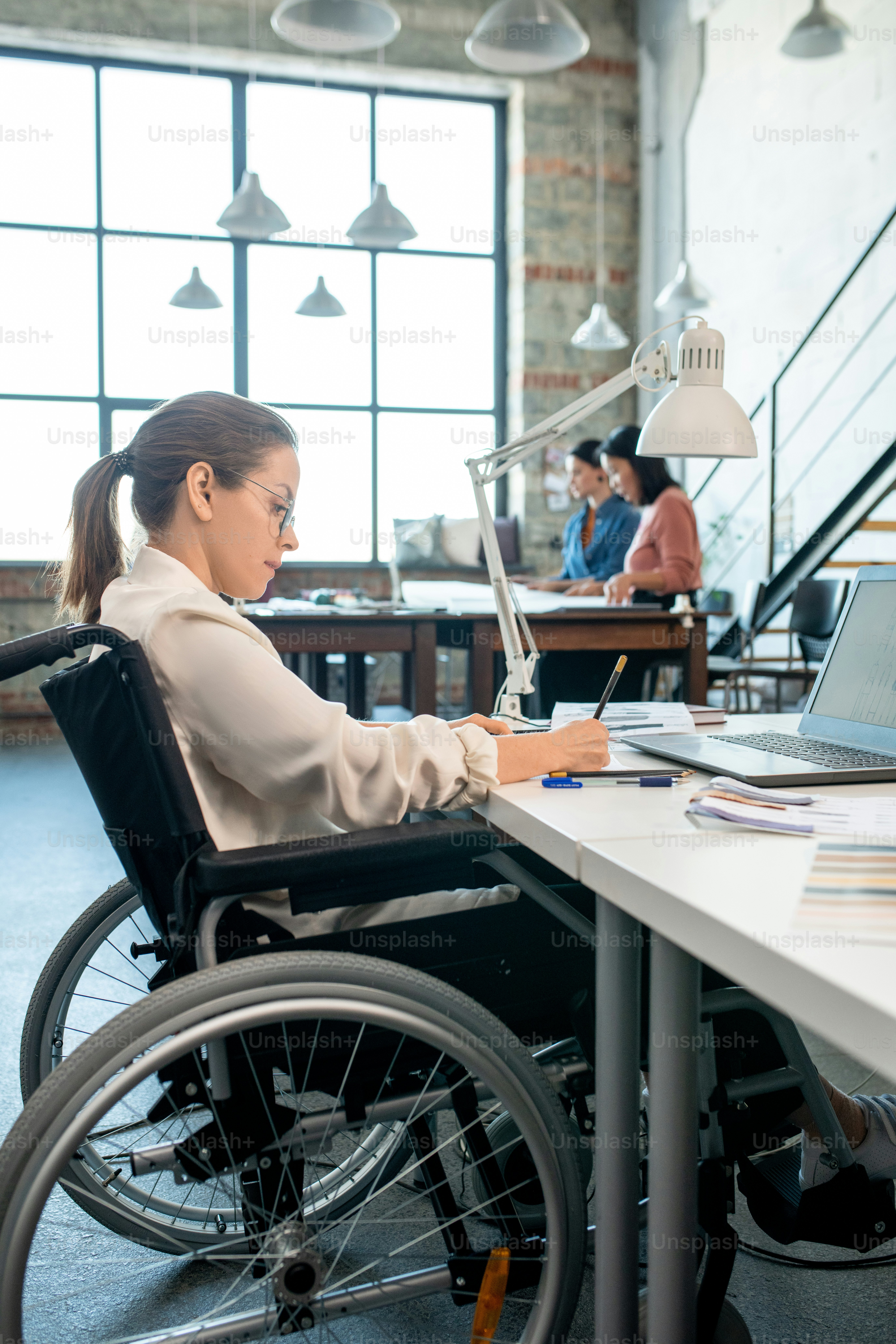 Fashion designer in wheelchair drawing sketches in notebook