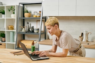 A person working on a laptop over wooden table in the kitchen