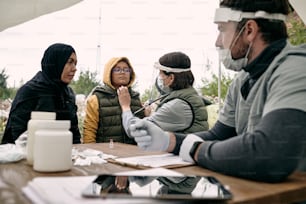 Medical specialist examining health of girland talking to her muslim mother outdoors