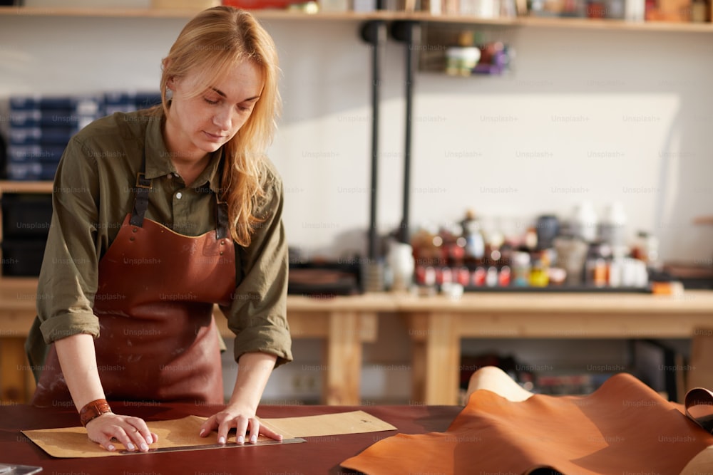 Retrato de cintura para arriba de una artesana que trabaja con cuero en el taller, espacio de copia