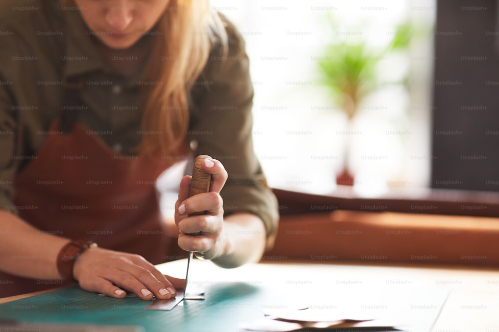 Closeup of unrecognizable female artisan making leather bag in workshop, copy space