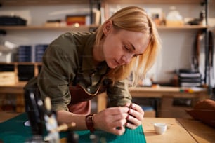Warmes Porträt einer Kunsthandwerkerin, die Ledertasche im Lederbearbeitungsatelier herstellt, Kopierraum