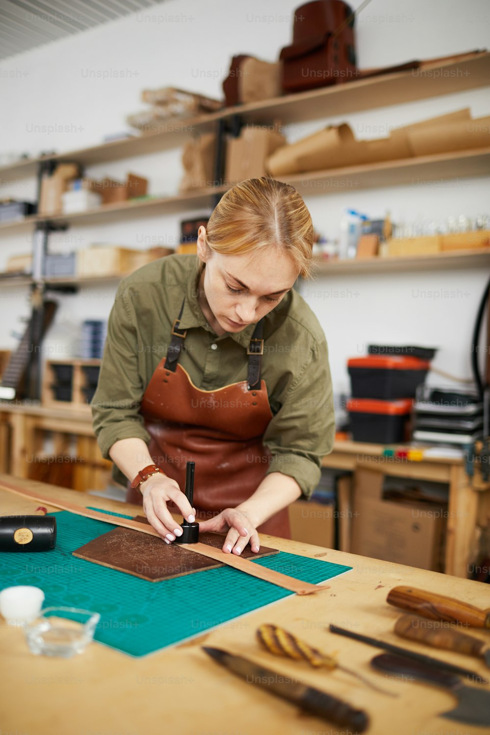 Porträt einer weiblichen Kunsthandwerkerin, die Lederstück in der Werkstatt misst, Kopierraum