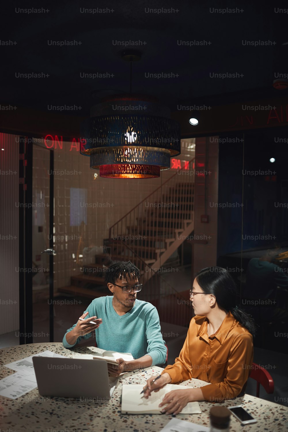 Retrato gran angular de dos empresarios étnicos discutiendo el proyecto mientras trabajan hasta tarde en la oficina oscura, espacio de copia