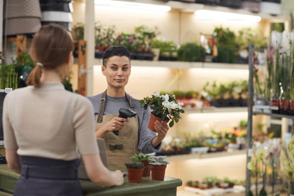 Waist up portrait of modern young woman selling flowers to customer in flower shop and smiling, copy space