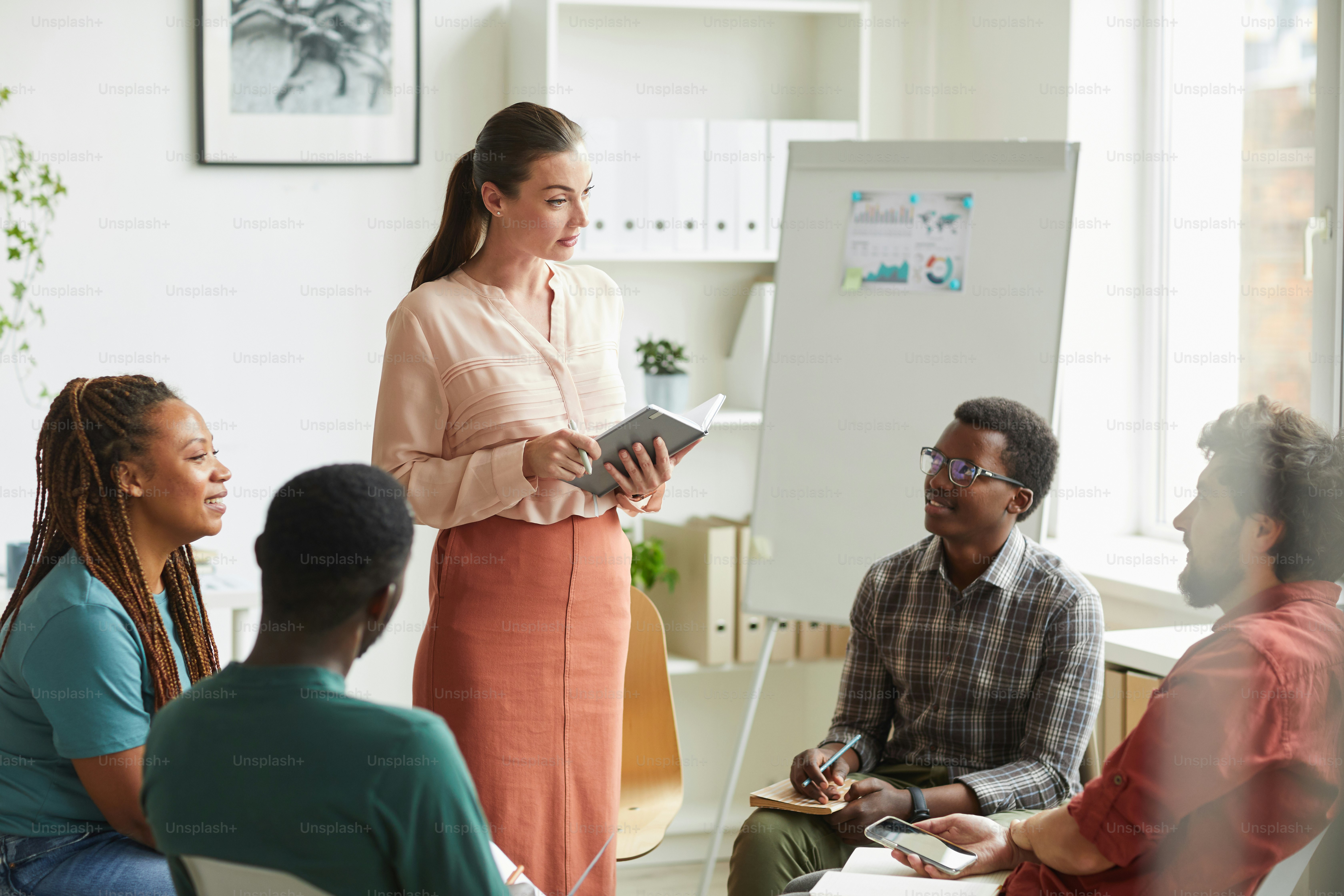 Grupo multiétnico de pessoas sentadas em círculo enquanto discutem a estratégia para o projeto de negócios no escritório, concentre-se na gerente feminina dando instruções, copie o espaço