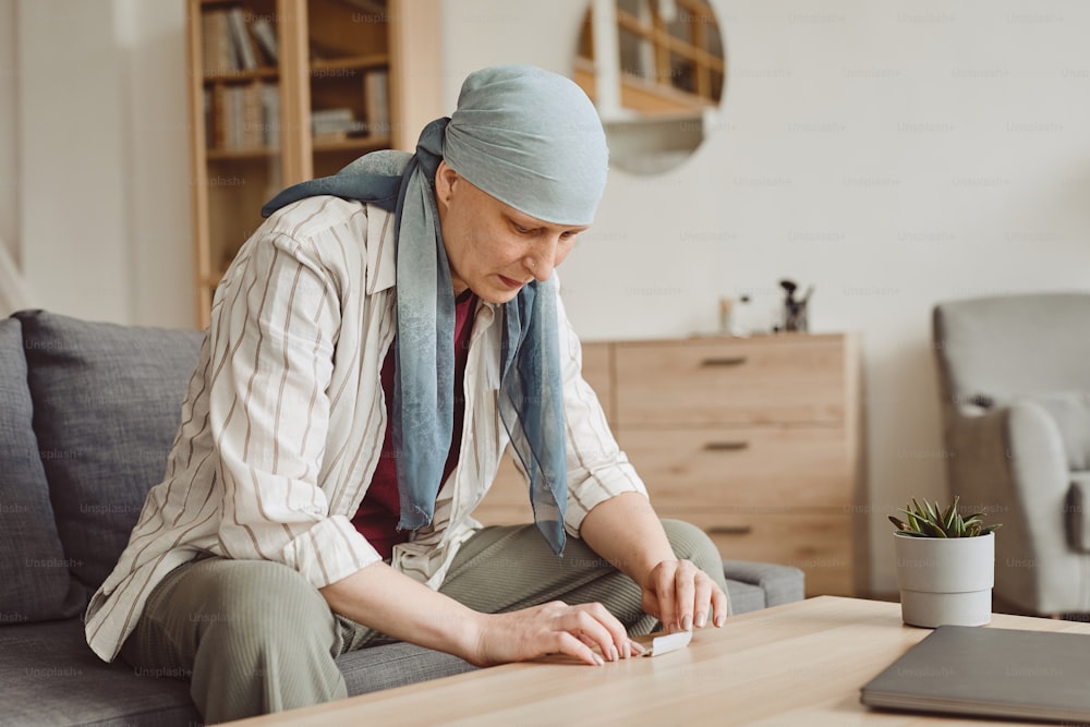 Warm toned portrait of bald adult woman taking marijuana for medicinal purposes in cancer recovery, copy space