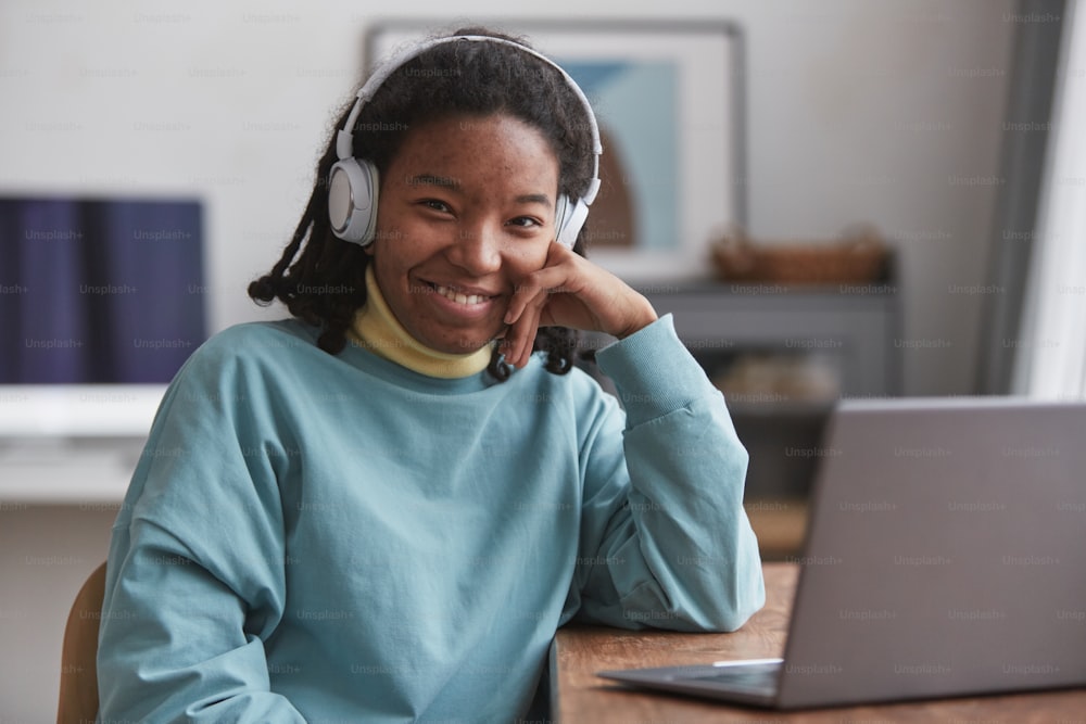 Portrait of real African American woman looking at camera and smiling while wearing headphones, focus on skin imperfections